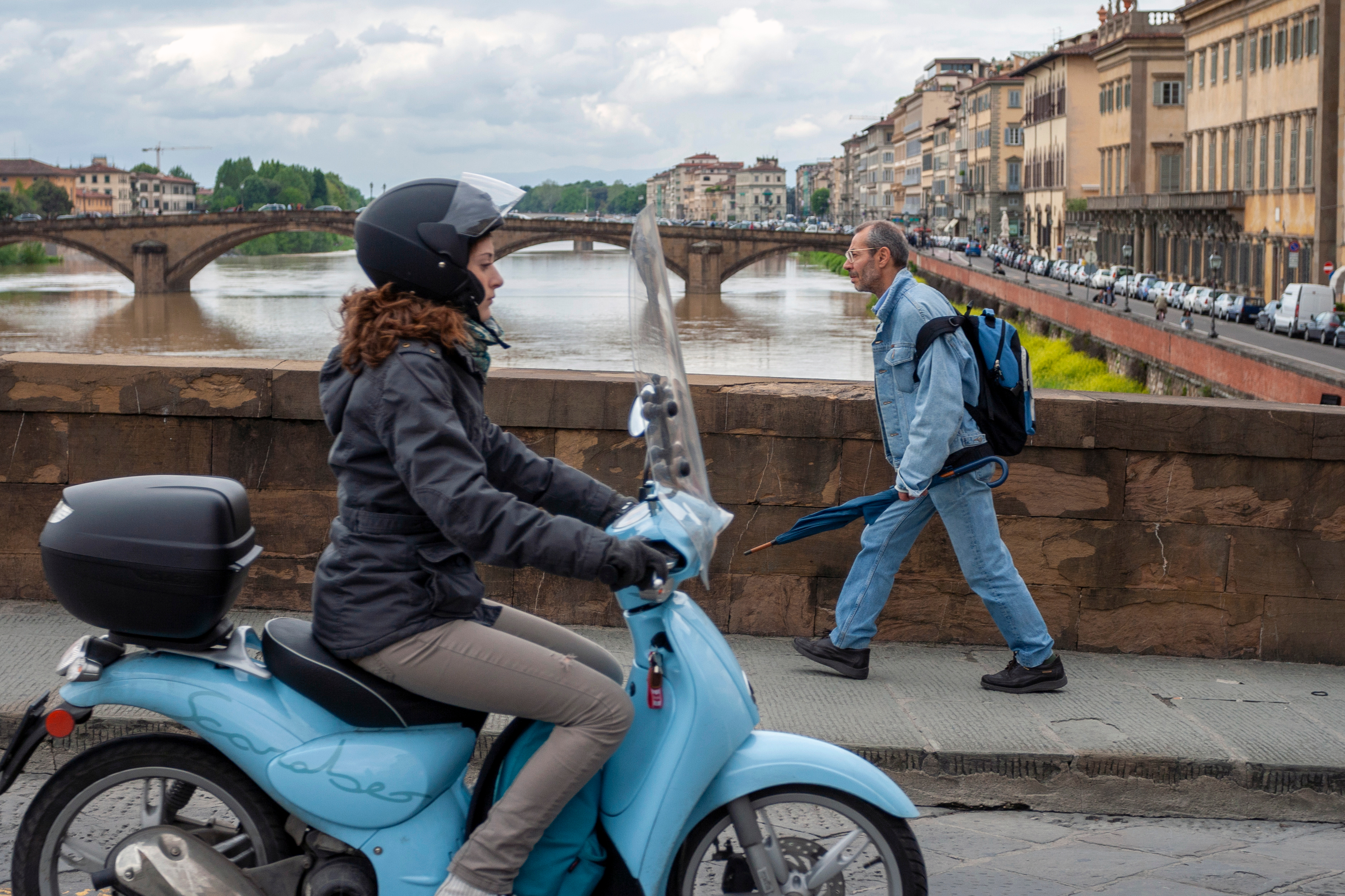 A women riding a vespa on a summer day in the streets of Florence.